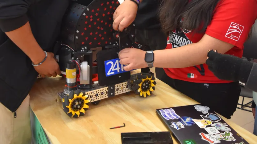 Integrantes de Ragnarok ajustan su robot de FTC, con el número 24198.